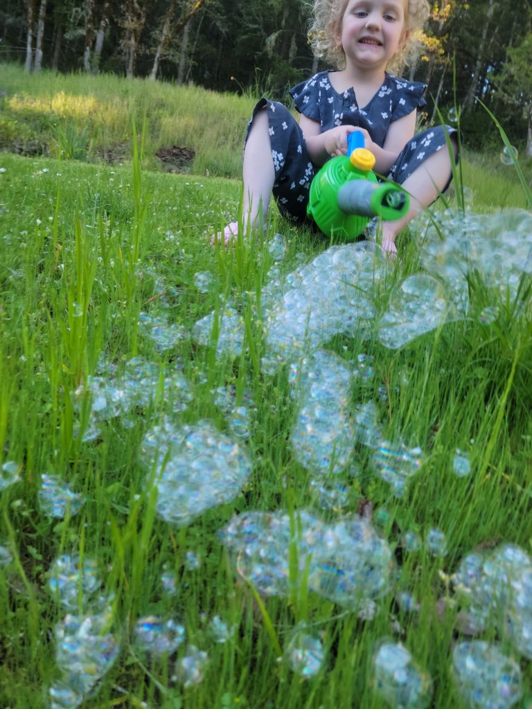 A child happily playing with bubbles in the grass